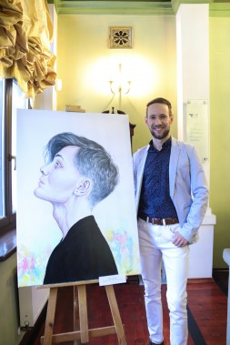Grzegorz Dyrda stojący przy sztaludze ze swoim obrazem