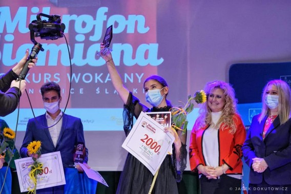 Zwyciężczyni zeszłorocznej edycji konkursu (Zofia Sydor) stoi na scenie i trzyma uniesioną…