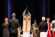 Aktorzy odgrywają scenę mszy prymicyjnej księdza Jana Machy. Jan w ornacie trzyma w uniesionych…