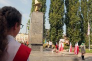 Pomnik Czynu Powstańczego - na pierwszym planie uczennica z biało-czerwoną szarfą na ramieniu.