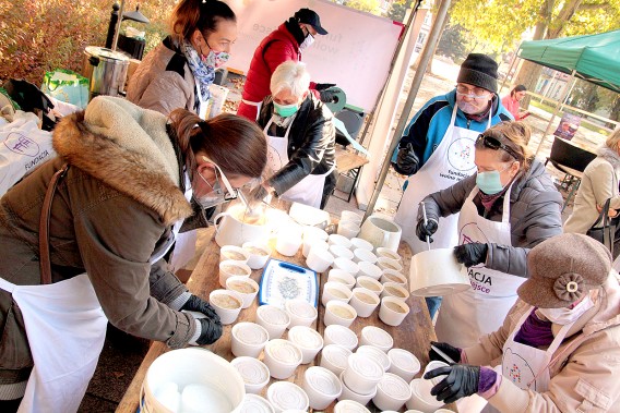 Zdjęcie wolontariuszy podających przy stole miseczki z żurem