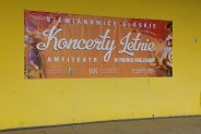 Baner reklamujący Koncerty Letniena tle żółtej ściany Amfiteatru