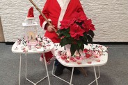 Mężczyzna w stroju mikołaja siedzący przy stoliku ze świątecznymi akcentami.