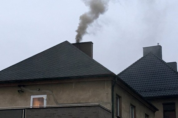 Czarny dym wydobywający się z komina na dachu domu