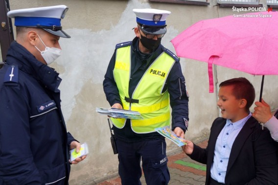 Policjanci wręczają chłopcu kolorowankę edukacyjną