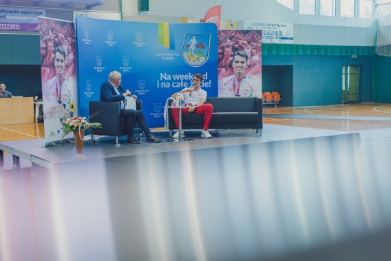 Robert Walczak i Kajetan Duszyński siedzą na podwyższeniu na środku boiska hali KS „Michał”