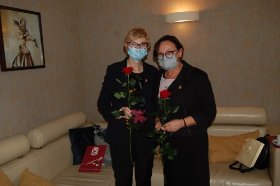 Dwie uczestniczki uroczystości z czerwonymi różami w rękach