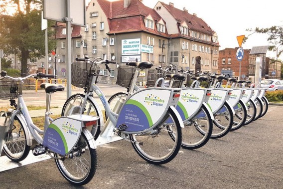 Osiem rowerów miejskich rozmieszczonych na jednej z samoobsługowych stacji rowerowych.