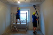 Dwóch pracowników budowlanych remontuje sufit i ściany, w jednym z lokali mieszkalnych.