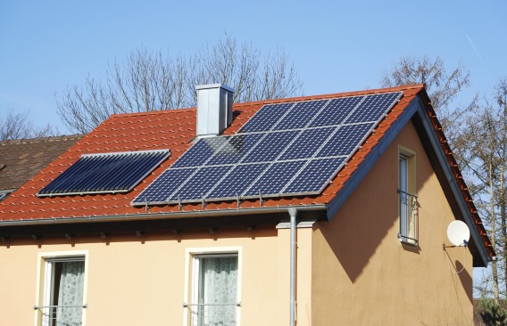 Panele słoneczne instalacji fotowoltaicznej na dachu domku jednorodzinnego.