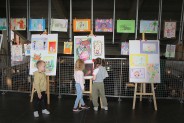 Dwie dziewczynki i chłopiec oglądają prace rysunkowe w holu SCK Park Tradycji.