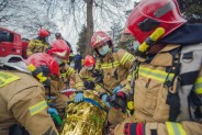 Strażacy okrywają folią termiczną leżącego na noszach
