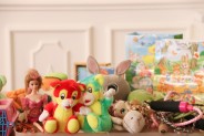 Na stole kolorowe zabawki m.in. lalka, pluszowe zwierzaki, skakanka, puzle