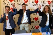 Trzech trzymających się za ręce uczniów na tle baneru "I love Śniadek"