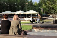 Gitarzysta Adam Bul podczas koncertu Chill Time przy Parku Tradycji. Ludzie siedzą na ławeczkach…