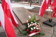 Płyta Grobu Nieznanego Żołnierza. Obok biało-czerwone flagi oraz kwiaty.