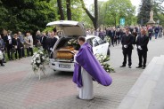 Ksiądz modlący się przed karawanem pogrzebowym w trakcie uroczystości