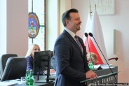 Prezydent miasta Rafał Piech stojący przy mównicy, udzielający informacji o działalności…