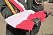 Złożona flaga Rzeczpospolitej Polskiej w rękach jednego ze strażaków, członków pocztu flagowego