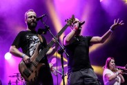 Dwaj muzycy zespołu Łydka Grubasa, ubrani w czarne koszulki, na scenie podczas koncertu. Jeden…