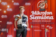 Jakub Lenc na tle czerwonej ścianki reklamowej konkursu
