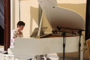 Na białym fortepianie gra Olga Dimczenko ubrana w kwiecistą bluzkę