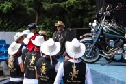 Zespół tańca liniowego, w białych kapeluszach kowbojskich i czarnych kamizelkach stoi w fosie…