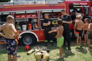 Przed wozem bojowym strażacy zapoznaja dzieci z wyposażeniem
