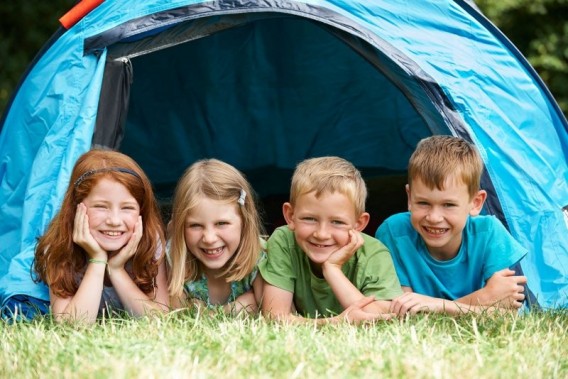 Czwórka uśmiechniętych dzieci pod namiotem.
