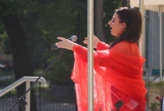 Swietłana Kaliniczenko ubrana w czerwoną suknię śpiewa do mikrofonu