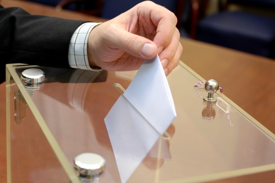 Dłoń trzymająca kartę wyborczą i wrzucająca ją do urny wyborczej