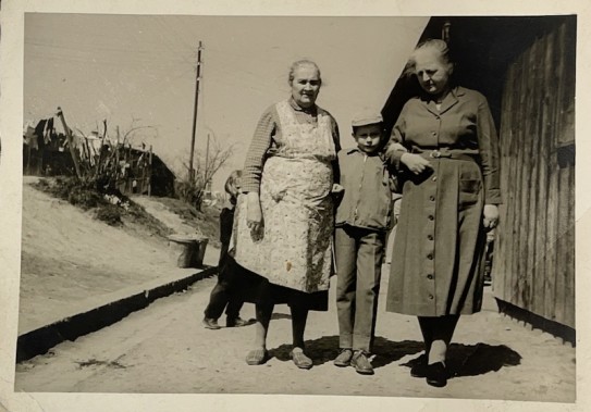 Zdjęcie przedstawia dwie starsze kobiety, stojące z małym chłopcem, pozujące do zdjęcia