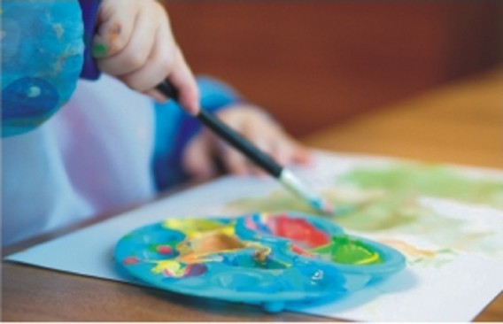 Na zdjęciu widoczne ręce dziecka trzymajace pędzel i malujące obrazek