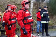 Po prawej strażak mówiący do mikrofonu, po lewej ratownicy