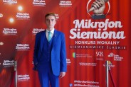 Norbert Kuświk na tle czerwonej ścianki reklamowej konkursu
