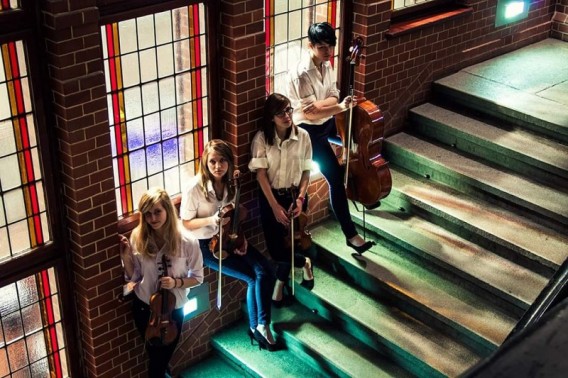 Na schodach na parapetach witrażowych okien siedzą dziewczyny z kwartetu smyczkowego Czortet z…