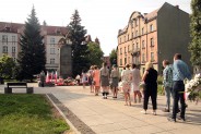 Mieszkańcy i delegacje zakładów pracy w kolejce z kwiatami przed Pomnikiem Czynu Powstańczego.