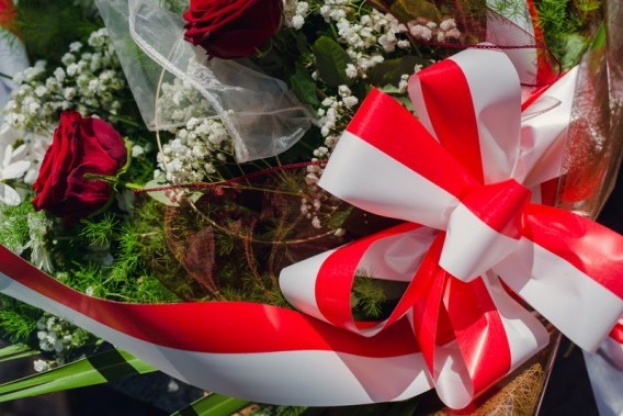 Kwiaty z biało-czerwoną wstążką pod pomnikiem