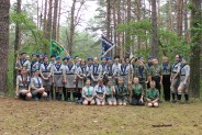Grupa harcerzy pozująca na tle lasu