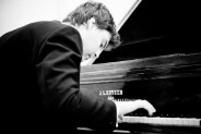 Na czarno-białej fotografi na fortepianie gra Michał Kryworuczko