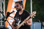 Industriada 2021 Występ zespołu KROKI Na pierszym planie gitarzysta zespołu na tle pomarańczowej…