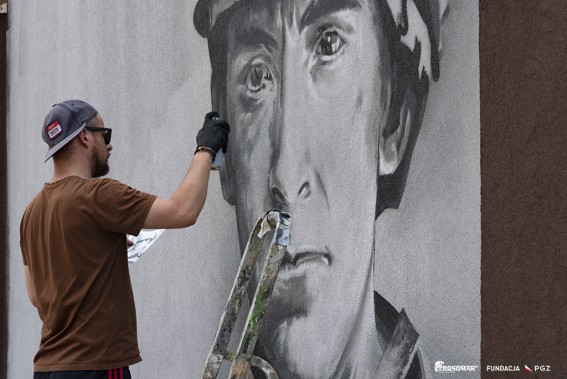 Artysta Wojciech Walczyk w malujący twarz na murze