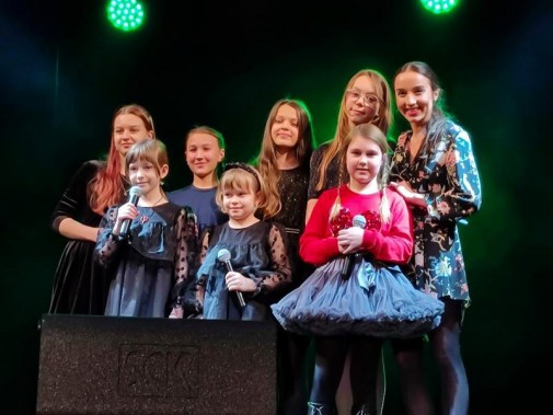 Na zdjęciu siedem dziewczynek ze studium wokalnego w SCK Bytków oraz ich instruktorka. Stoją na…