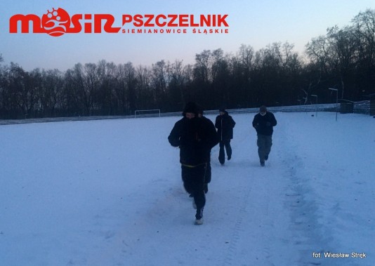 Grupa czterech osób biega po bieżni lekkoatletycznej w Parku Pszczelnik.