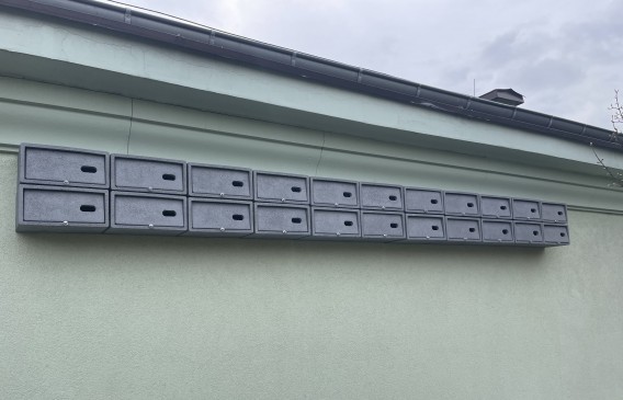 Budki dla jerzyków zamontowane na ścianie budynku szkolnego.