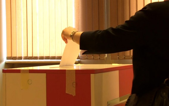 Człowiek wrzucający kartę do głosowania do urny wyborczej