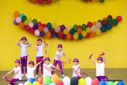 Na żółtym tle sceny amfiteatru wiszą kolorowe balony. Na scenie występuje dziecięcy zespół…