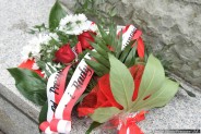 Wiązanka kwiatów z biało-czerwoną szarfą leżąca na cokole pomnika Wojciecha Korfantego w…