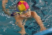 Finały okręgu w pływaniu dzieci z rodzin wielodzietnych - na zdjęciu pływające dziecko z deską do…