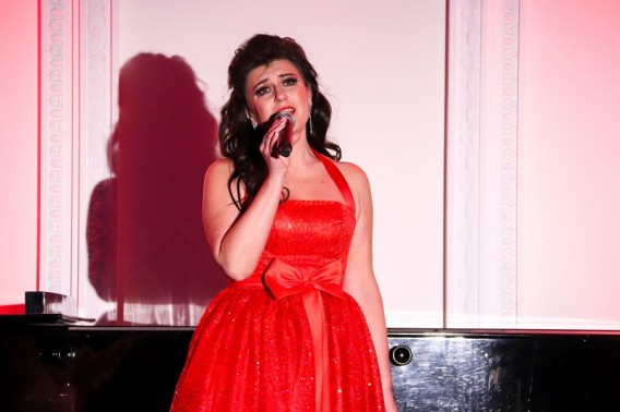 Na scenie Aleksandra Stokłosa ubrana w czerwoną wieczorową sukienkę z mikrofonem w ręce